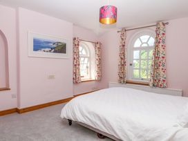 A bedroom with a bed and windows at Gorway Cottage in Teignmouth