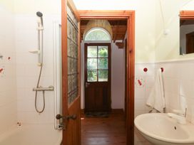 A bathroom with a shower, sink, and door at Gorway Cottage Teignmouth