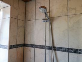 A shower head and wall tiles in the bathroom at Gorway Cottage Teignmouth