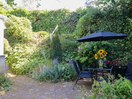 A garden with a table and chairs under an umbrella at Gorway Cottage in Teignmouth