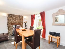 A dining room with a stone fireplace and wooden table at Swallow Cottage Sheviock near Crafthole