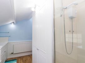 A bathroom with a shower, radiator, and shelf at Swallow Cottage in Sheviock near Crafthole