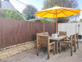 A garden with a wooden table and chairs under a yellow umbrella at Swallow Cottage in Sheviock near Crafthole