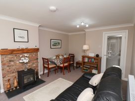 A living room with a fireplace and dining table at Wheeldale Cottage in Goathland