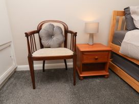 A bedroom with a chair, bedside table, and lamp at Wheeldale Cottage in Goathland