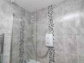 A bathroom with a shower and tiled walls at Wheeldale Cottage in Goathland