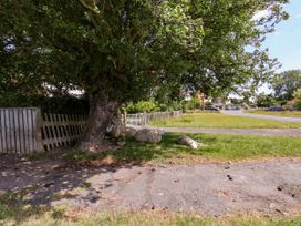 A scene with a tree and sheep resting on grass by the road at Wheeldale Cottage in Goathland