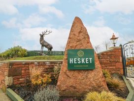 A sign for Hesket Caravan Park with a deer statue at the entrance of the park in Carlisle
