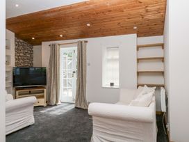 A living room with a television and door at The Headmasters Quarters in Chudleigh