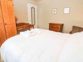 A bedroom with a bed, wardrobe, table, and chair at 8 Yellow Sands in Padstow