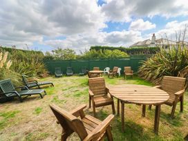 A garden with wooden furniture and lounge chairs at 8 Yellow Sands in Padstow