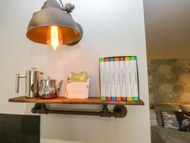 A shelf with a light fixture, teapot, coffee pot, and books at La'al Yan in Branthwaite