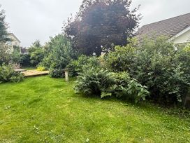 A garden with grass, trees, and wooden decking at La'al Yan in Branthwaite
