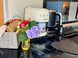 A kitchen with a coffee machine, kettle, and flowers at La'al Yan in Branthwaite