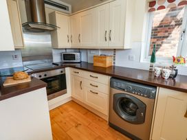 A kitchen with an oven, microwave, and washing machine at Little Gem in Weymouth