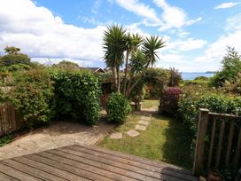 A garden with a pathway and palm tree at Little Gem in Weymouth