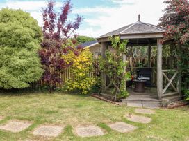 A garden with a gazebo and plants at Little Gem in Weymouth