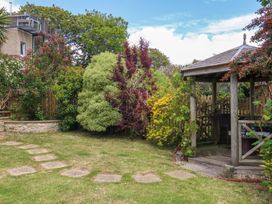 A garden with a gazebo and pathway at Little Gem in Weymouth