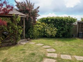 A garden with a gazebo and stepping stones at Little Gem in Weymouth