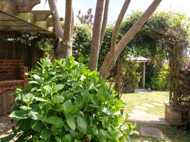 A garden featuring trees, a barbecue, and a stone path at Little Gem in Weymouth