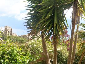 A garden with palm trees and ruins in the background at Little Gem in Weymouth