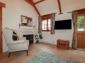 A living room with an armchair and television at Cider Cottage