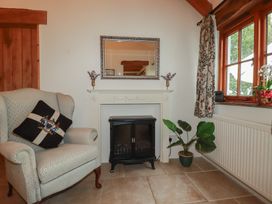 A living room with an armchair and a fireplace at Cider Cottage
