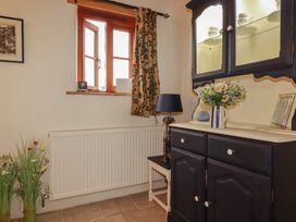A dining room with a cupboard and flowers at Cider Cottage