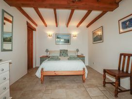 A bedroom with a bed and chair at Cider Cottage