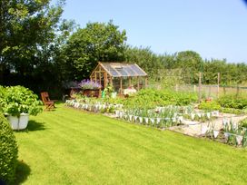 A garden with a greenhouse and vegetable beds at Cider Cottage near Launceston