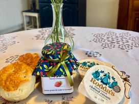 A kitchen table with scones, jam, clotted cream, and a vase at Cider Cottage near Launceston