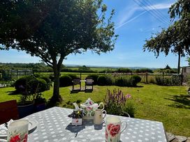 A garden with a table and chairs overlooking fields at Cider Cottage near Launceston