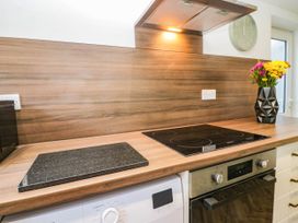 A kitchen with an induction hob, oven, and washing machine at 24 Harrington Road Workington