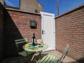 An outdoor patio with a table, chairs, wine bottle, and glasses at 24 Harrington Road Workington