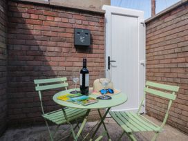 A table with chairs and a bottle in an outdoor seating area at 24 Harrington Road Workington