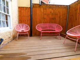 An outdoor area with pink chairs and wooden flooring at Wick Cottage in Whitby