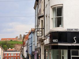 A street view with shops and a hilltop castle in the background at Wick Cottage in Whitby
