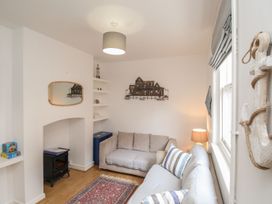 A living room with a sofa, lamp, and mirror at Pixie Cottage in Weymouth