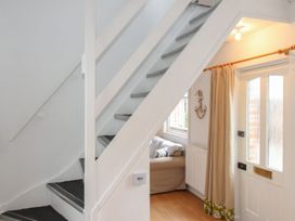 A hallway with a staircase and a front door at Pixie Cottage in Weymouth