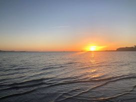 A view of a sunset over the sea with distant ships at Pixie Cottage in Weymouth