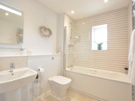 A bathroom with a bathtub, sink, toilet and window at Lapwings, Aldeburgh
