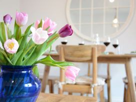 A dining room with a vase of tulips and a wooden table at Lapwings, Aldeburgh