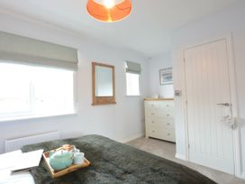 A bedroom with a bed and dresser at Lapwings, Aldeburgh