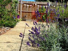 A garden with lavender, paving stones, and a red metal table and chairs at Lapwings, Aldeburgh