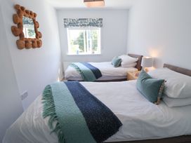 A bedroom with two beds and a lamp on a nightstand at Lapwings, Aldeburgh
