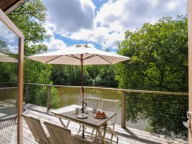 An outdoor seating area with table and chairs near a river at 11 Water's Edge near Pelynt