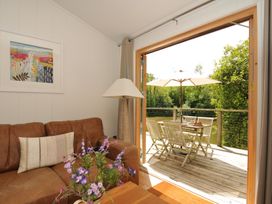 A living room with a sofa, lamp and door to a deck at 11 Water's Edge near Pelynt