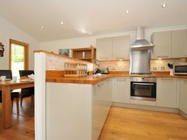 A kitchen with cabinets and a dining table at 11 Water's Edge near Pelynt