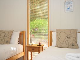 A bedroom with two beds and a lamp on a wooden table at 11 Water's Edge near Pelynt