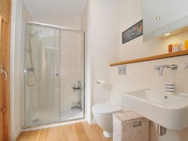 A bathroom with a shower, toilet, and sink at 11 Water's Edge near Pelynt